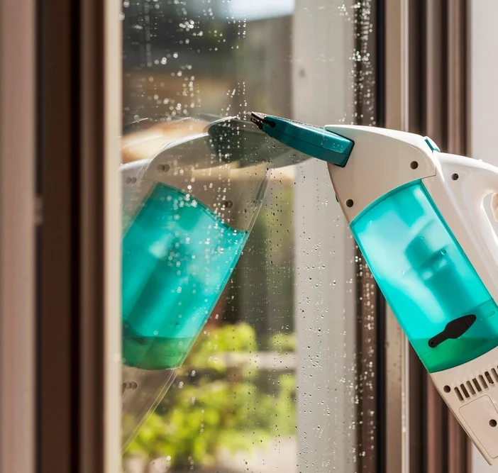 Electric window vacuum cleaning water droplets off a glass window pane.