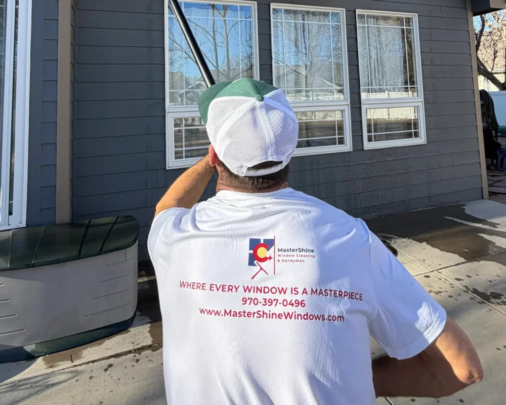 MasterShine technician in white branded t-shirt cleaning upper windows with pole.